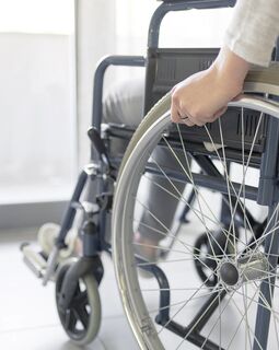 Person im Rollstuhl vor Balkontür