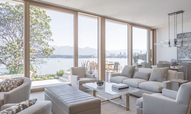 Blick aus hellem Wohnraum auf Terrasse und See durch UNILUX Holz-Alu Hebe-Schiebeanlage