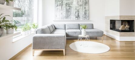Modernes helles Wohnzimmer mit grauer Couch vor Kamin