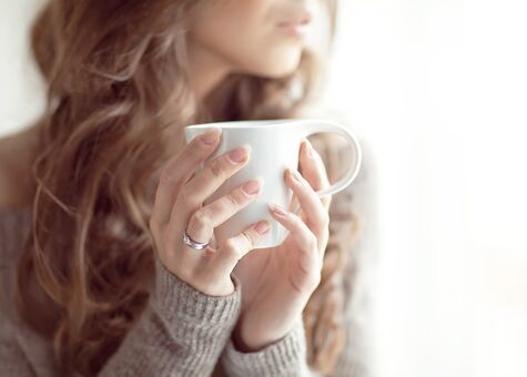 Junge Frau mit Tasse vor Fenster