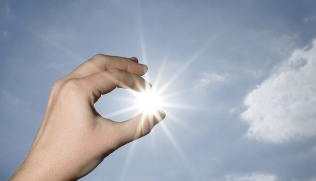 Hand hält Sonne zwischen Fingern Symbolbild