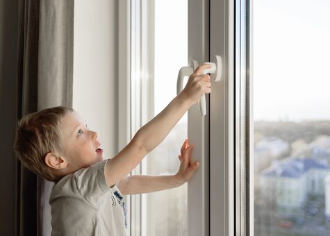Junge öffnet UNILUX Kunststofffenster mit UNILUX Fenstergriff Standard