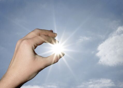 Hand hält Sonne zwischen Fingern Symbolbild
