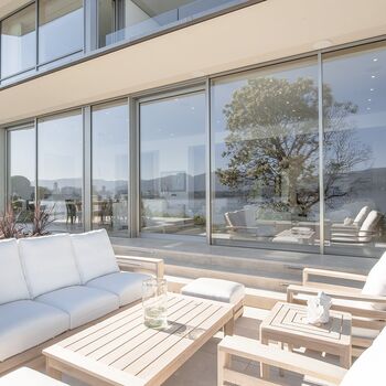 Blick von sonniger Terrasse auf großformatige UNILUX Holz-Alu Hebe-Schiebe Anlage