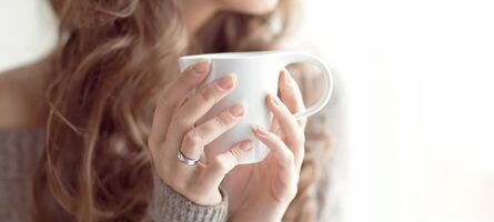 Junge Frau mit Tasse vor Fenster