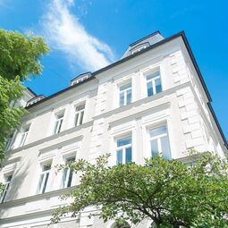 Fassade Stadtvilla mit UNILUX Holz Meisterfenster Denkmal vor blauem Himmel