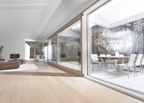 Heller moderner Innenraum mit UNILUX FineLine Pfosten-Riegel-Fassade aus Holz und Alu und UNILUX Hebe-Schiebe Anlage Holz-Alu
