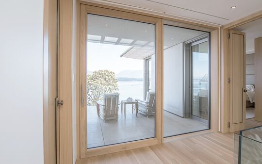 Blick aus Wohnraum auf Balkon durch geöffnete UNILUX Holz-Alu Hebe-Schiebe Anlage