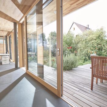 Büroraum mit geöffneter UNILUX Holz-Alu Hebe-Schiebe Anlage und Blick auf Terrasse
