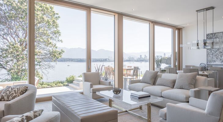 Blick aus hellem Wohnraum auf Terrasse und See durch UNILUX Holz-Alu Hebe-Schiebeanlage