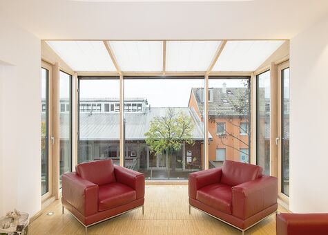Wimnertgarten oder Balkon mit Balkontüren aus Holz in hellem Wohnbereich mit großen Holzfenstern