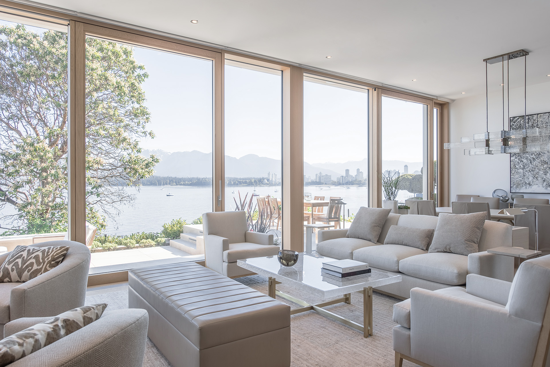 Blick aus hellem Wohnraum auf Terrasse und See durch UNILUX Holz-Alu Hebe-Schiebeanlage